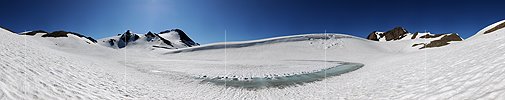 Panoramabild Schneebedeckter Bergsee mit hellblauem Wasserstreifen und Wächte